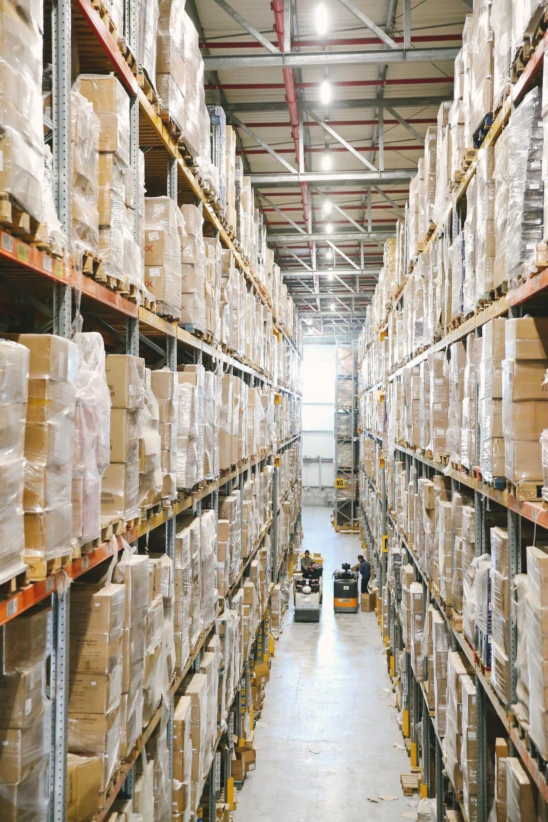 Allée d'entrepôt logistique avec palettes filmées en rayonnage